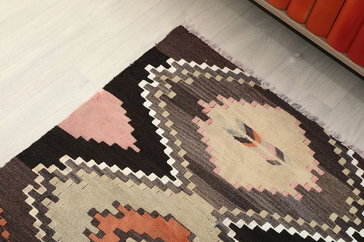 Angled close-up of the rug's beige and orange geometric sections and border detail