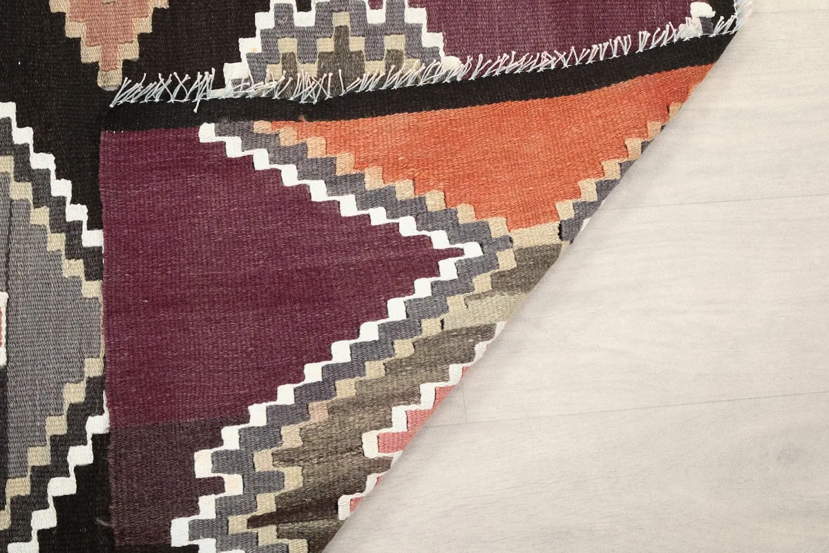 Close-up of the rug's corner, showing the low wool pile and the rich purple and orange colors