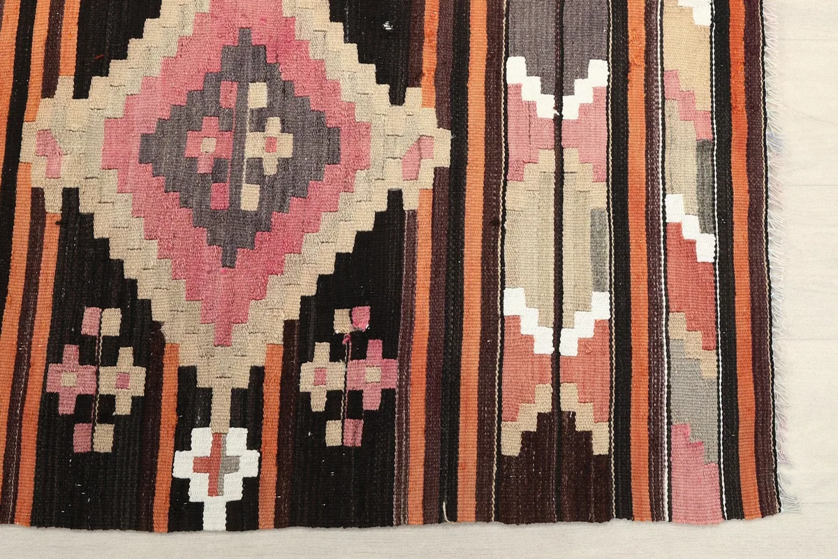 Detailed view of the hand-knotted geometric motifs in pink, beige, and black