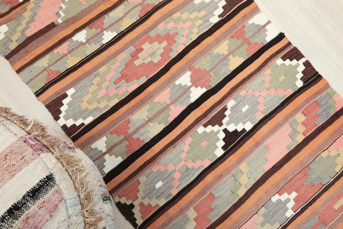 Overhead angled shot highlighting the rug's vibrant pink, orange, and brown stripes