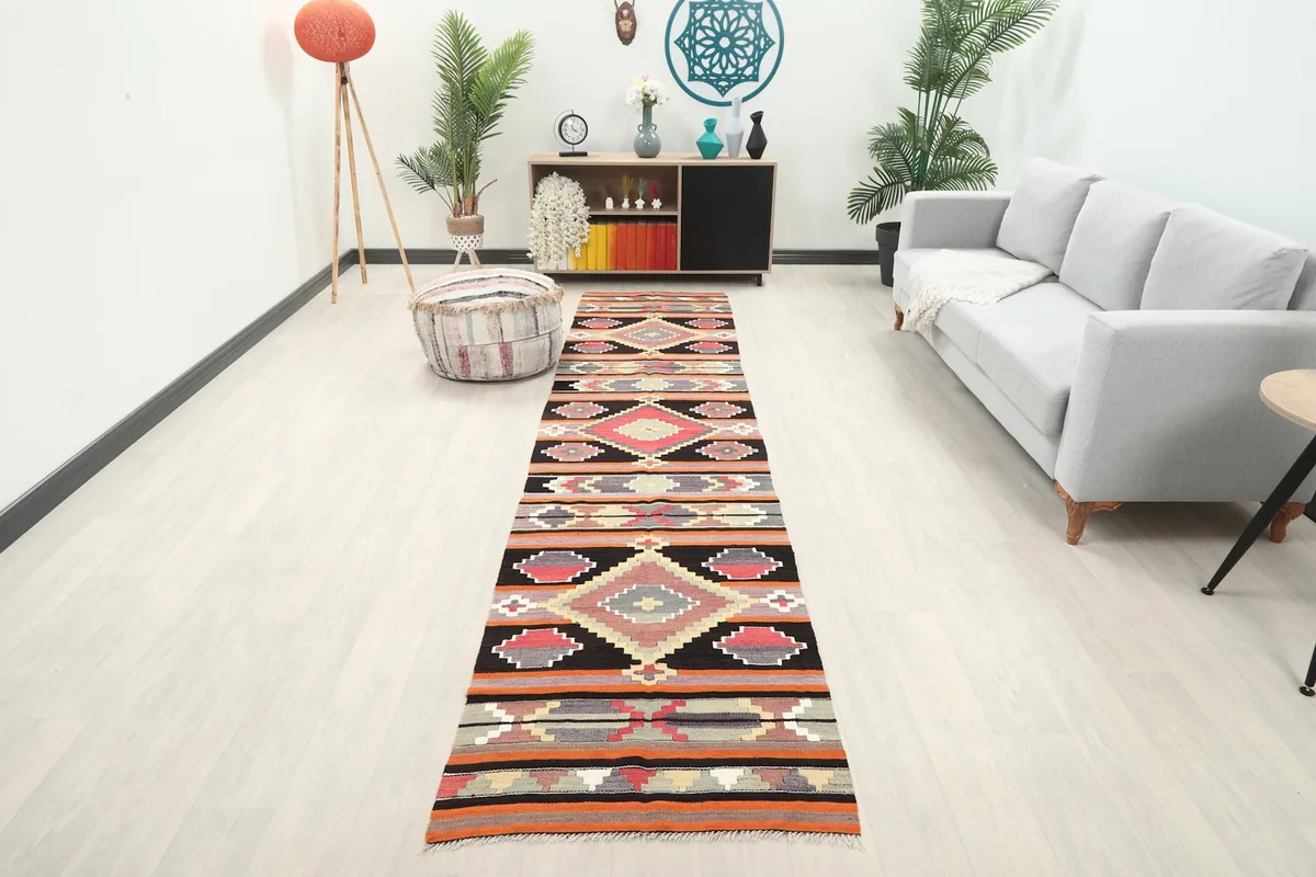 Full view of the runner rug in a bright room with a sofa and plants, showcasing its length and pattern.