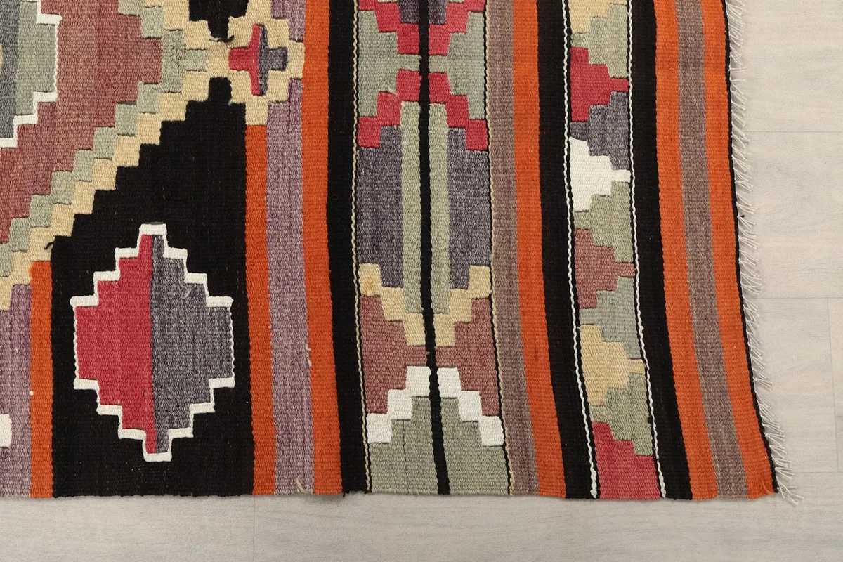 Detailed close-up of the rug's hand-knotted wool pile and fringe, revealing the intricate weaving and color variations.