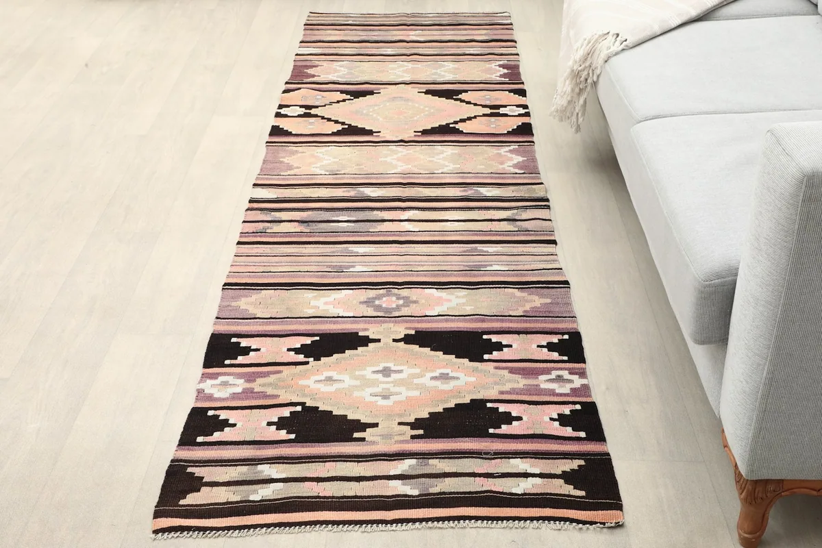 Runner rug placed in a room setting on a light floor next to a sofa, showing its length