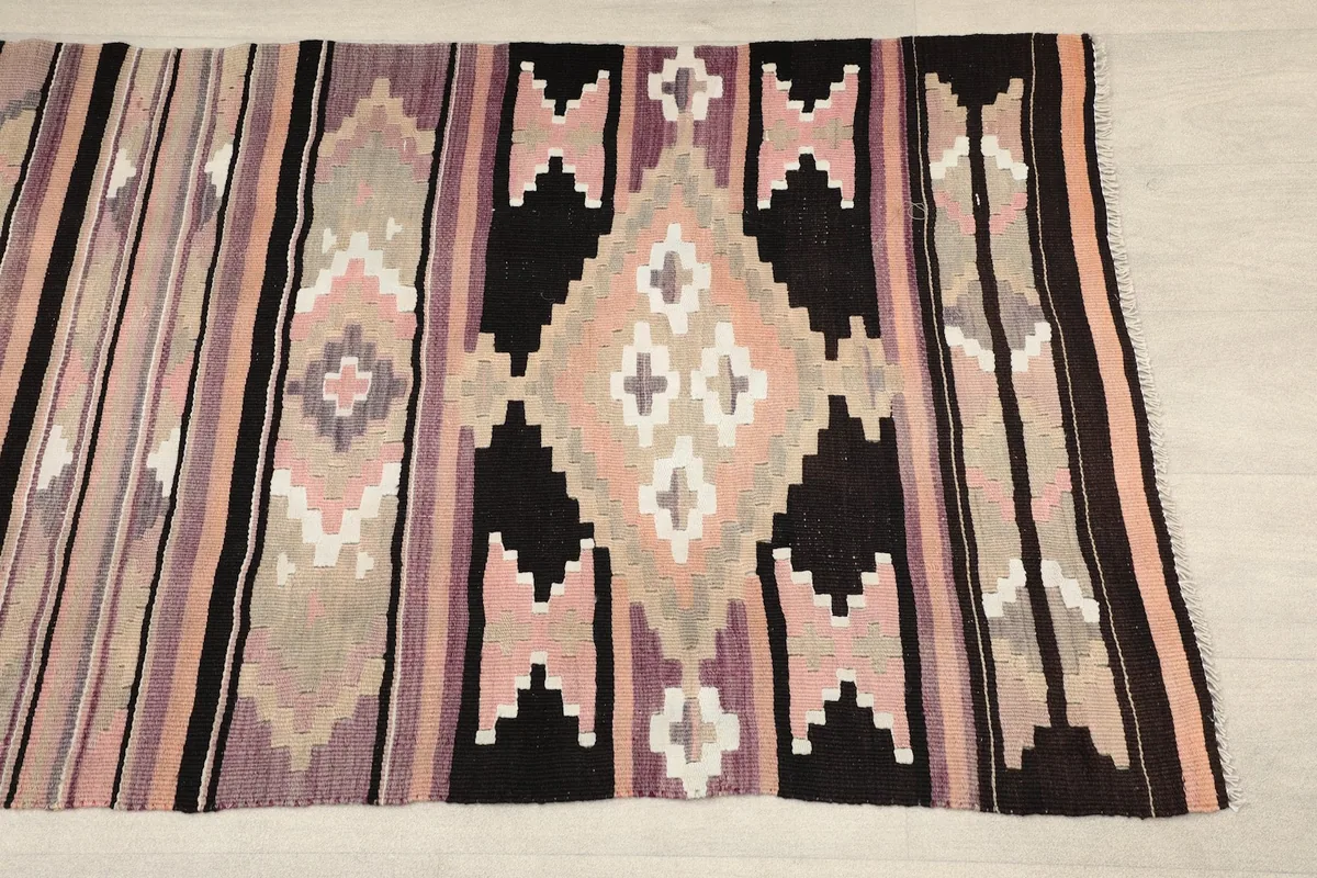 Close-up of the central geometric motifs in beige, rose, black, and purple colors