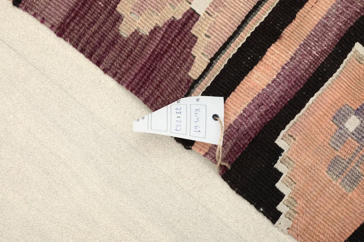 Corner of the rug with a tag showing size and origin details, against a light background