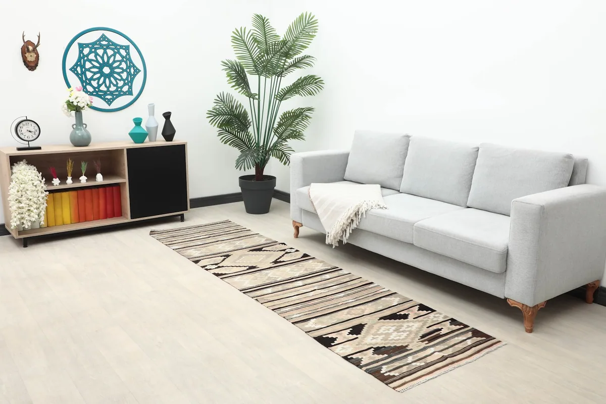 Long view of the runner rug in a room with a sofa, side table, and plant