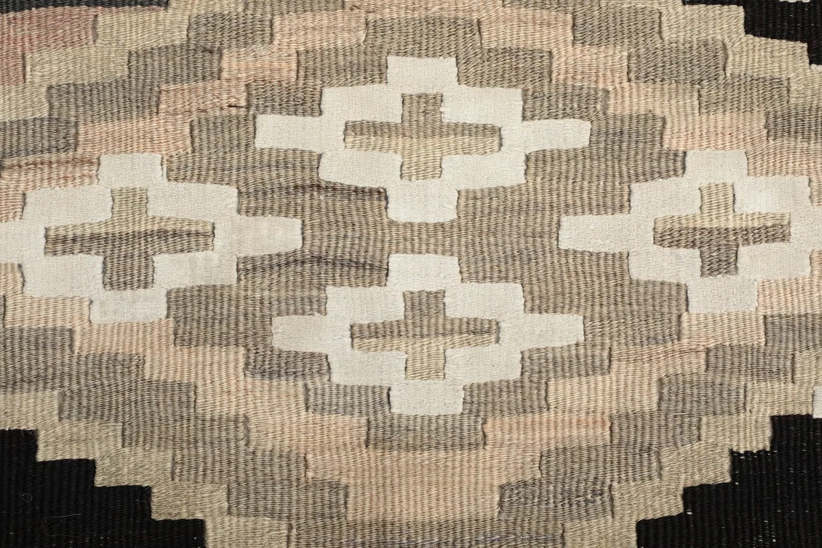 Macro view of the hand-knotted low wool pile and intricate geometric stitching