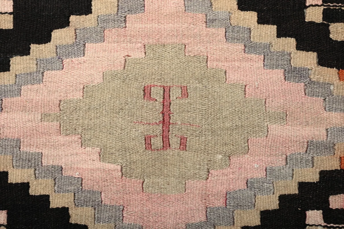 Extreme close-up of a geometric motif within a diamond, showing wool texture and color variations
