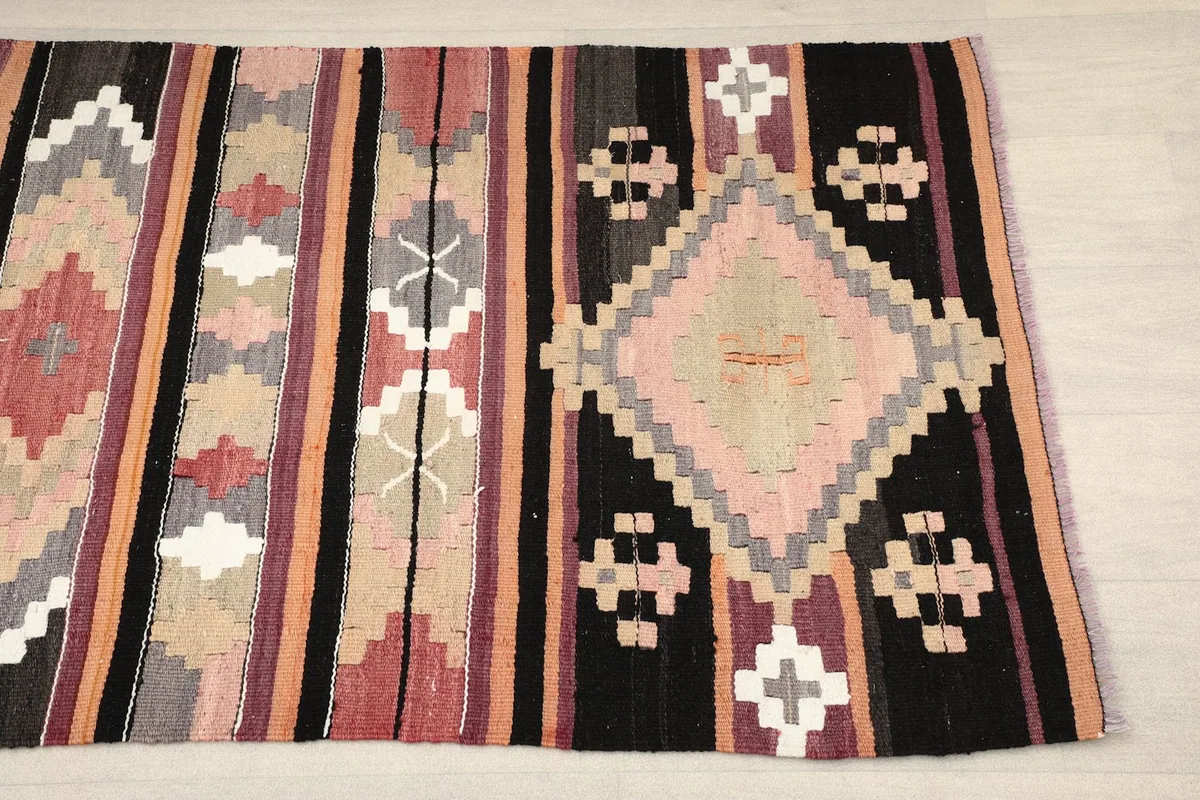 Close-up of one end of the rug, showing a large rose and gray geometric diamond motif