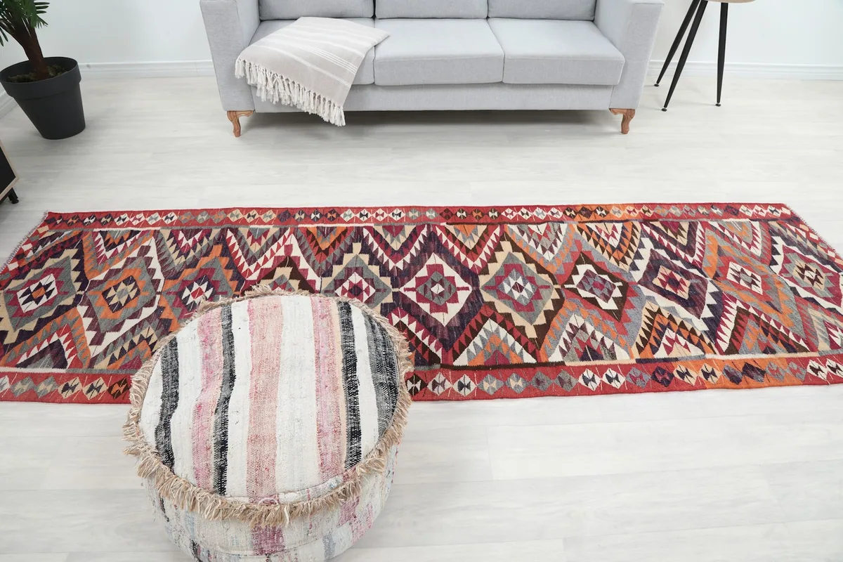 Wide shot of the red runner rug centered in a room with a light gray sofa and ottoman