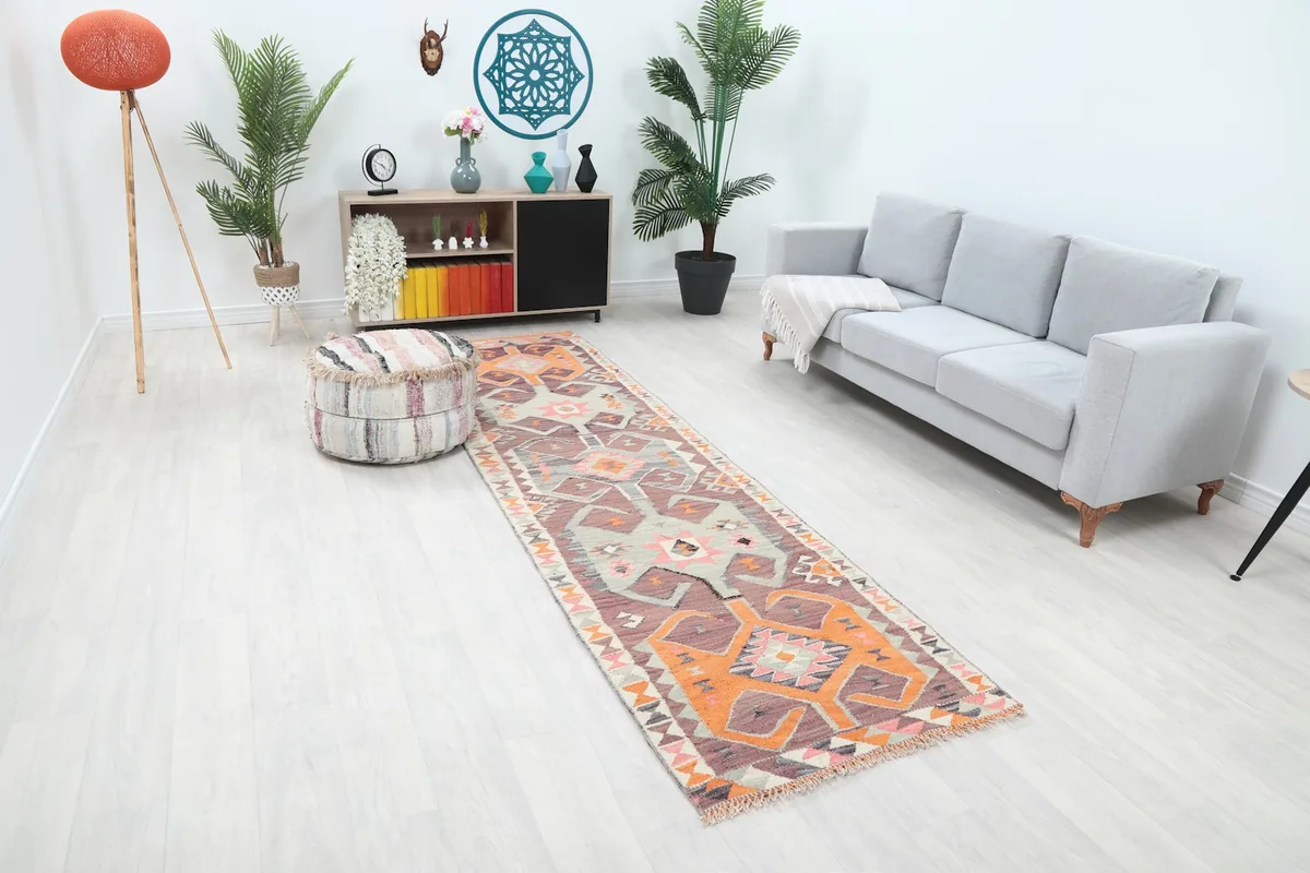 Angled view of the vintage runner rug in a living space, highlighting its length and placement between furniture.
