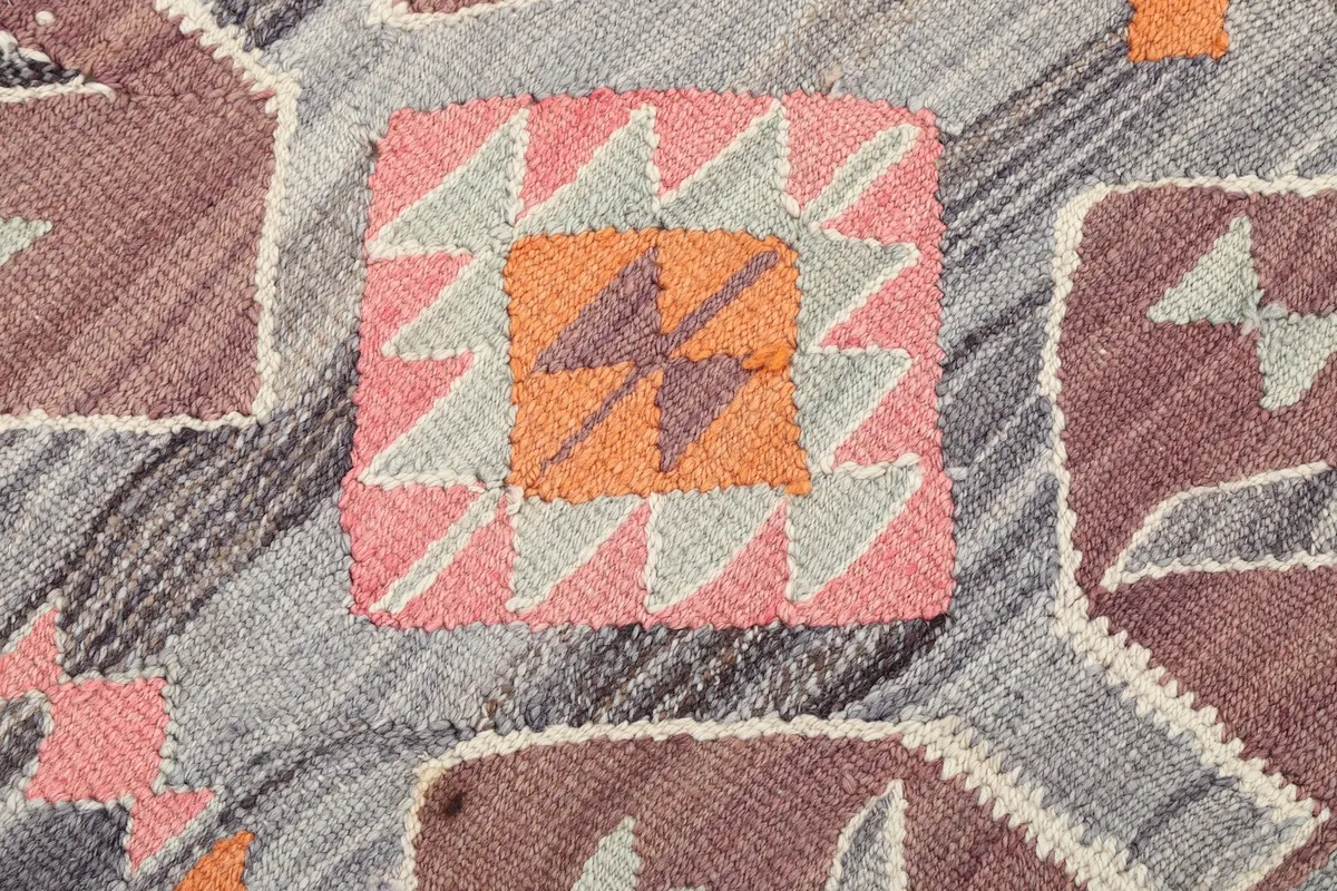 Macro detail of a central geometric motif on the rug, revealing the texture of the hand-knotted wool pile.