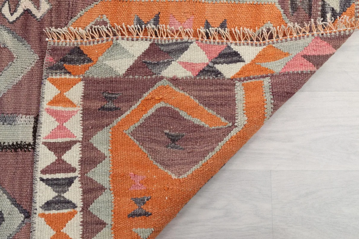 Underside view of the folded rug, showing the cotton foundation and the hand-knotted structure.