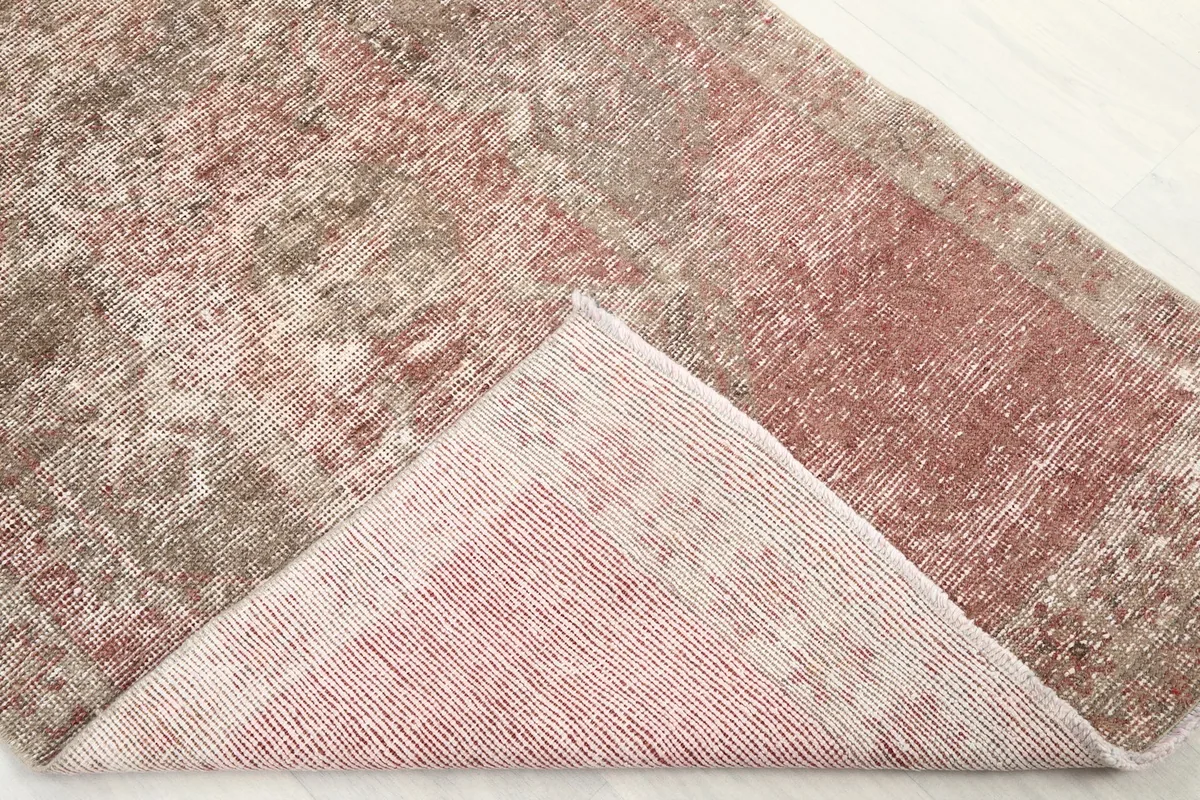 Corner of the rug folded back to reveal the back of the rug and the pile