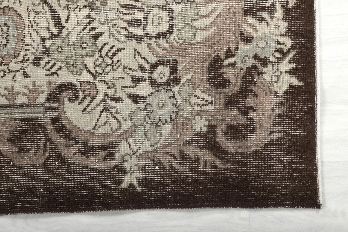 Detail of the charcoal border and beige floral motifs on the rug