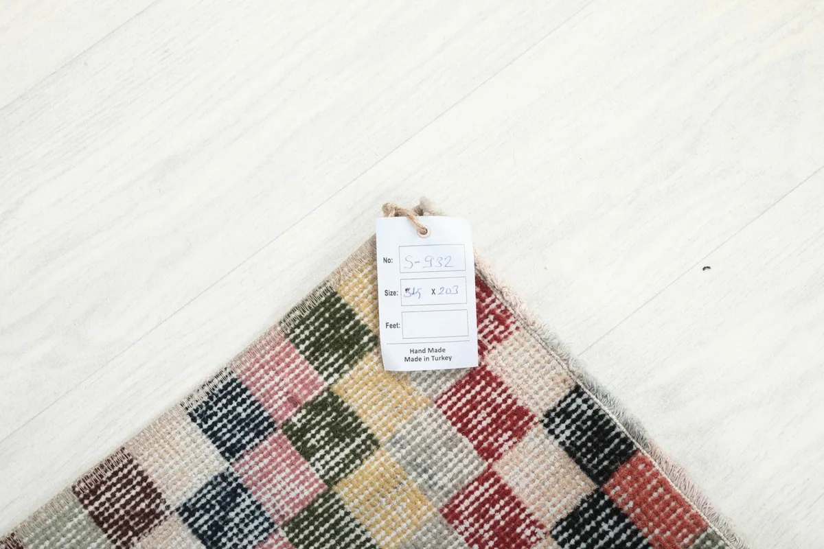 Corner of the multicolor rug with the product tag showing size and origin details.