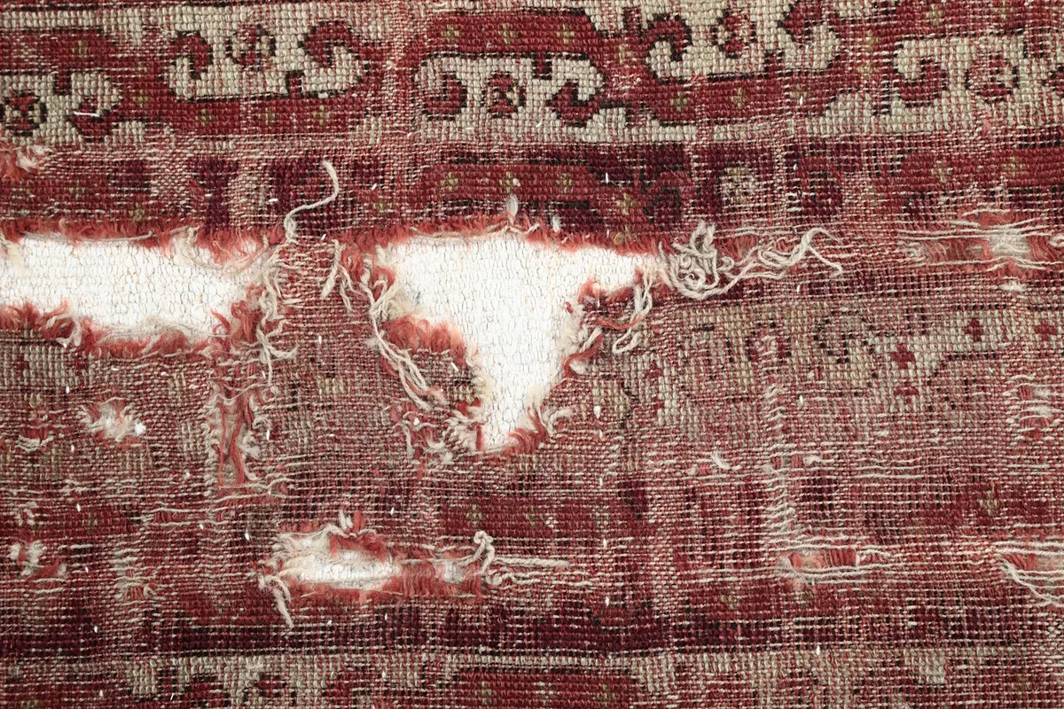 Close-up of the low wool pile, showing the distressed texture and visible cotton foundation.