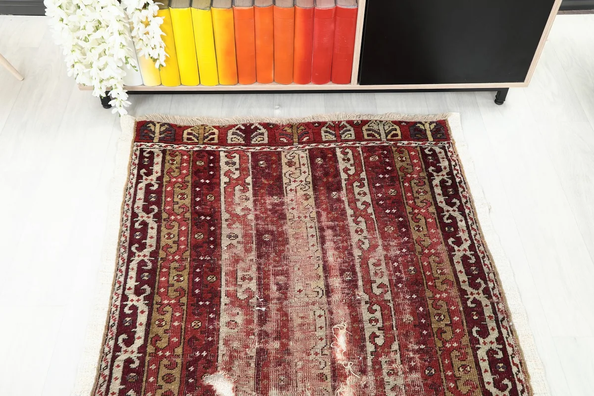 Overhead view of one end of the red runner rug, displaying its geometric and striped motifs.