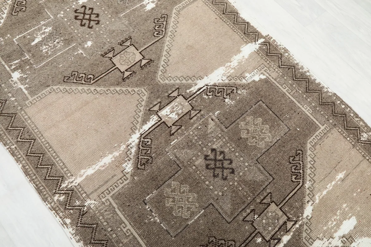 Close-up detail of the beige and brown geometric motifs and worn pile