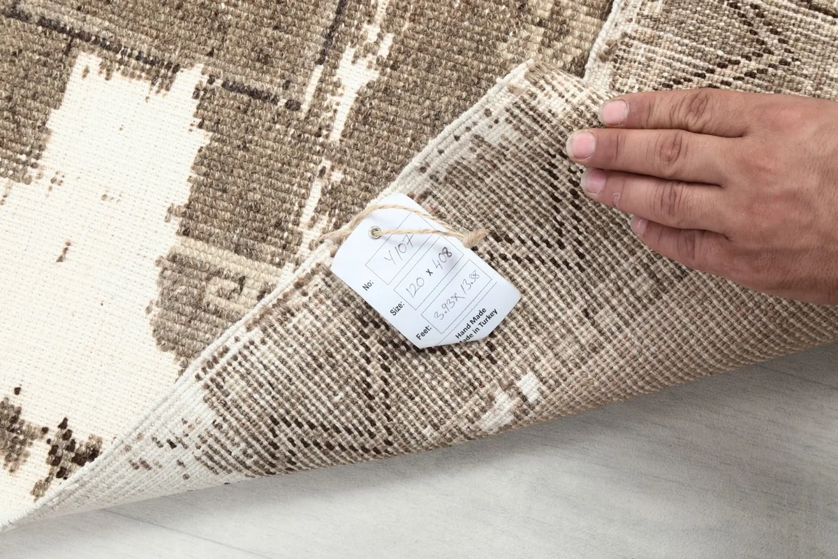 Hand holding a tag on the back of the vintage Anatolian runner rug