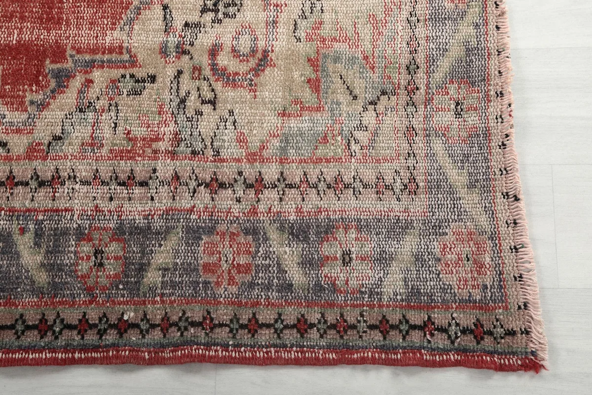 Detail of the rug's border design featuring blue, beige, and red geometric patterns