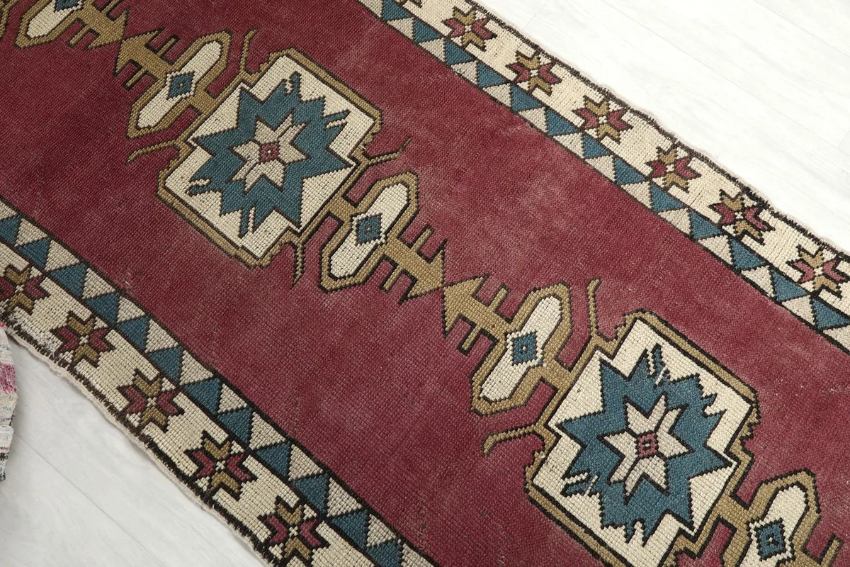 Upper angle view showing the repeated central geometric motifs in blue, beige, and gold on the rose field