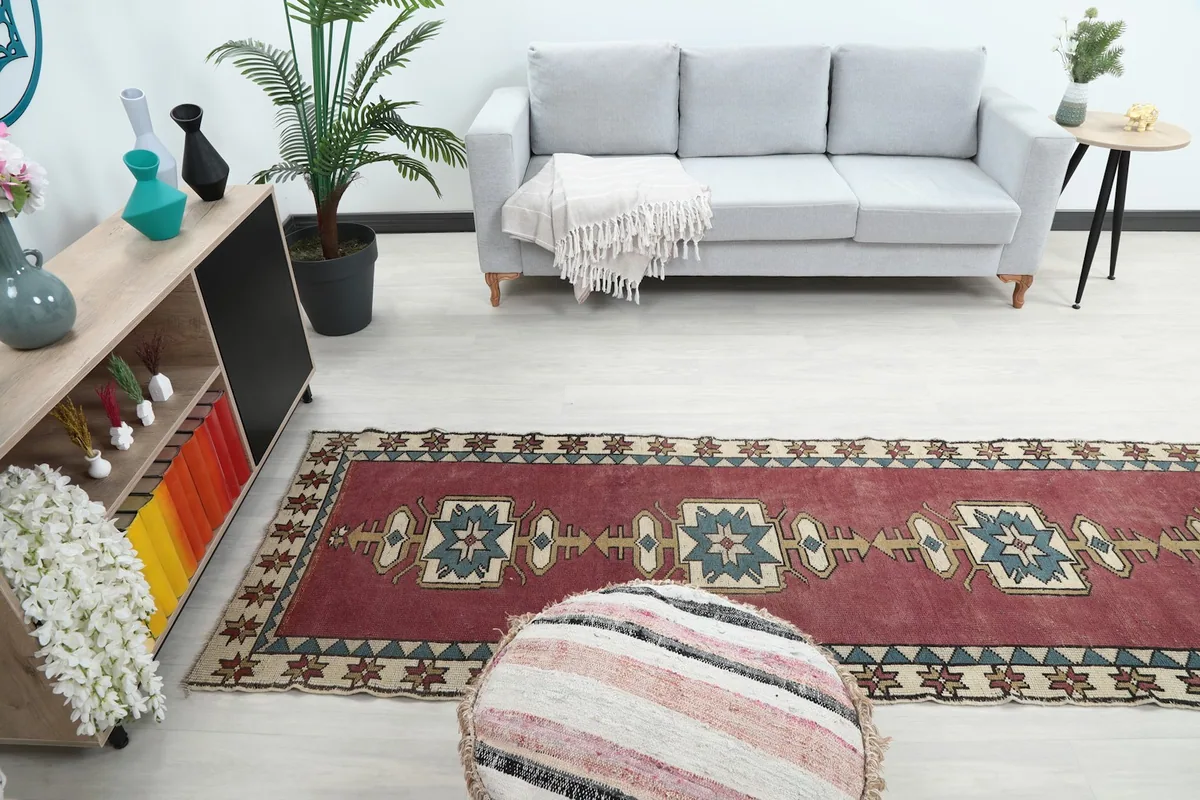 View of the runner rug from a different angle in the room, with a sofa and pouf in the foreground