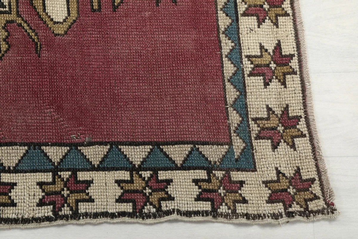 Detailed view of the rug's beige border with blue triangles and multi-color star motifs