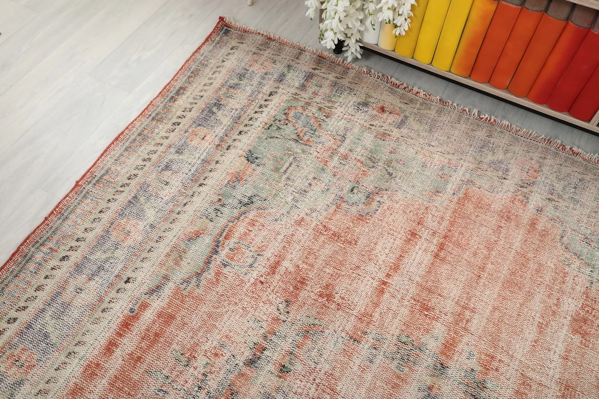 Corner view of the rug, illustrating the gentle wear and the blend of rust and blue tones.