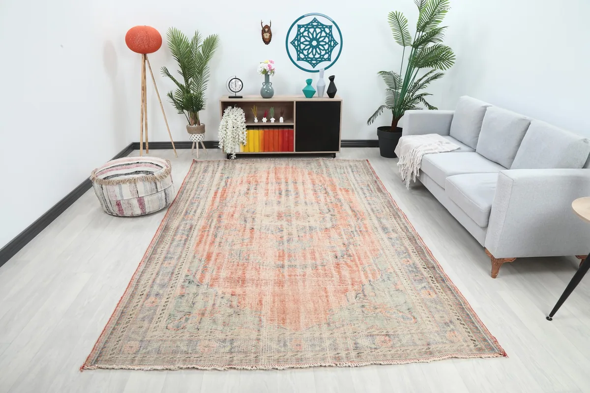 Rust and blue vintage rug placed in a modern living room setting with a light gray sofa.