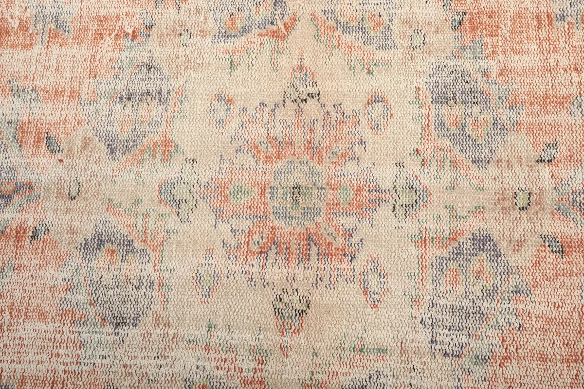 Central medallion detail, showcasing the intricate, faded motifs in rust, blue, and ivory.