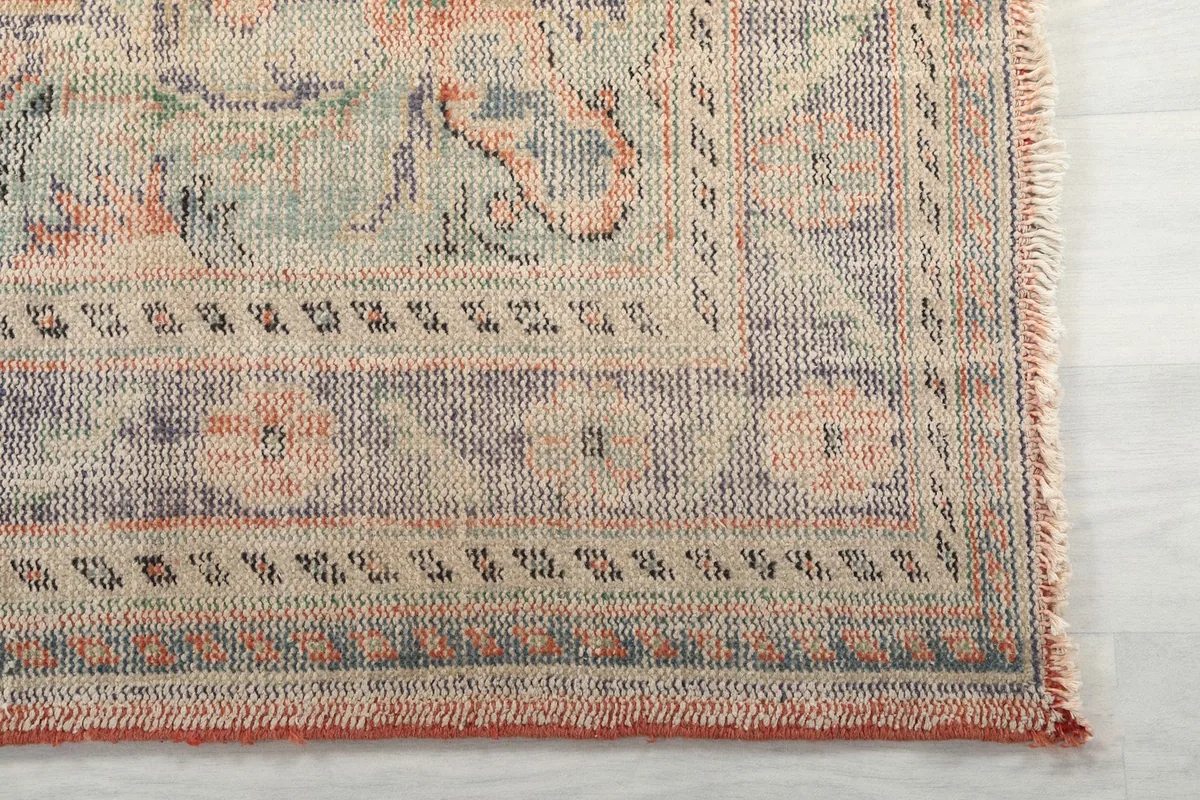 Detail of the rug's border design featuring geometric patterns and muted blue and rust hues.