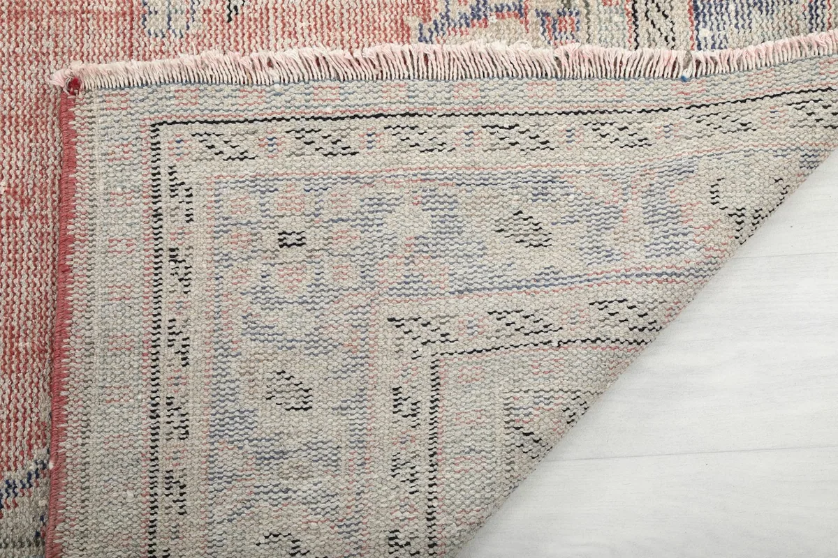Close-up of the rug's reverse side, showing the knotting and fringe