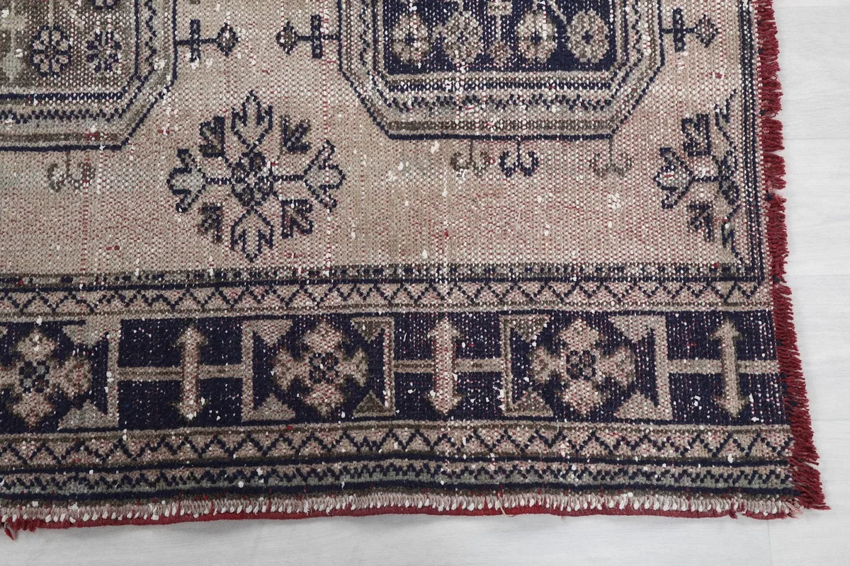 Detail of the navy geometric border and the faded red edge of the rug