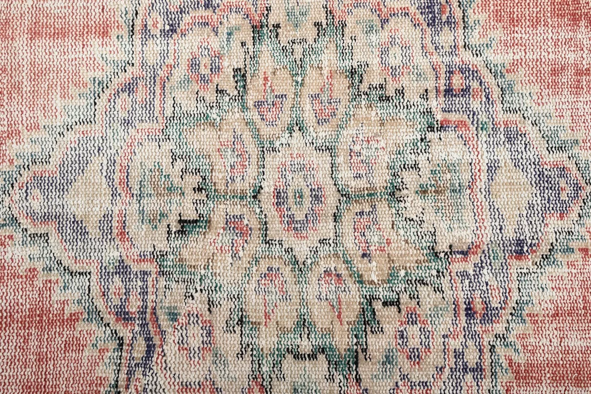 Detailed view of the medallion's faded blue, green, and beige motifs against the rose background.