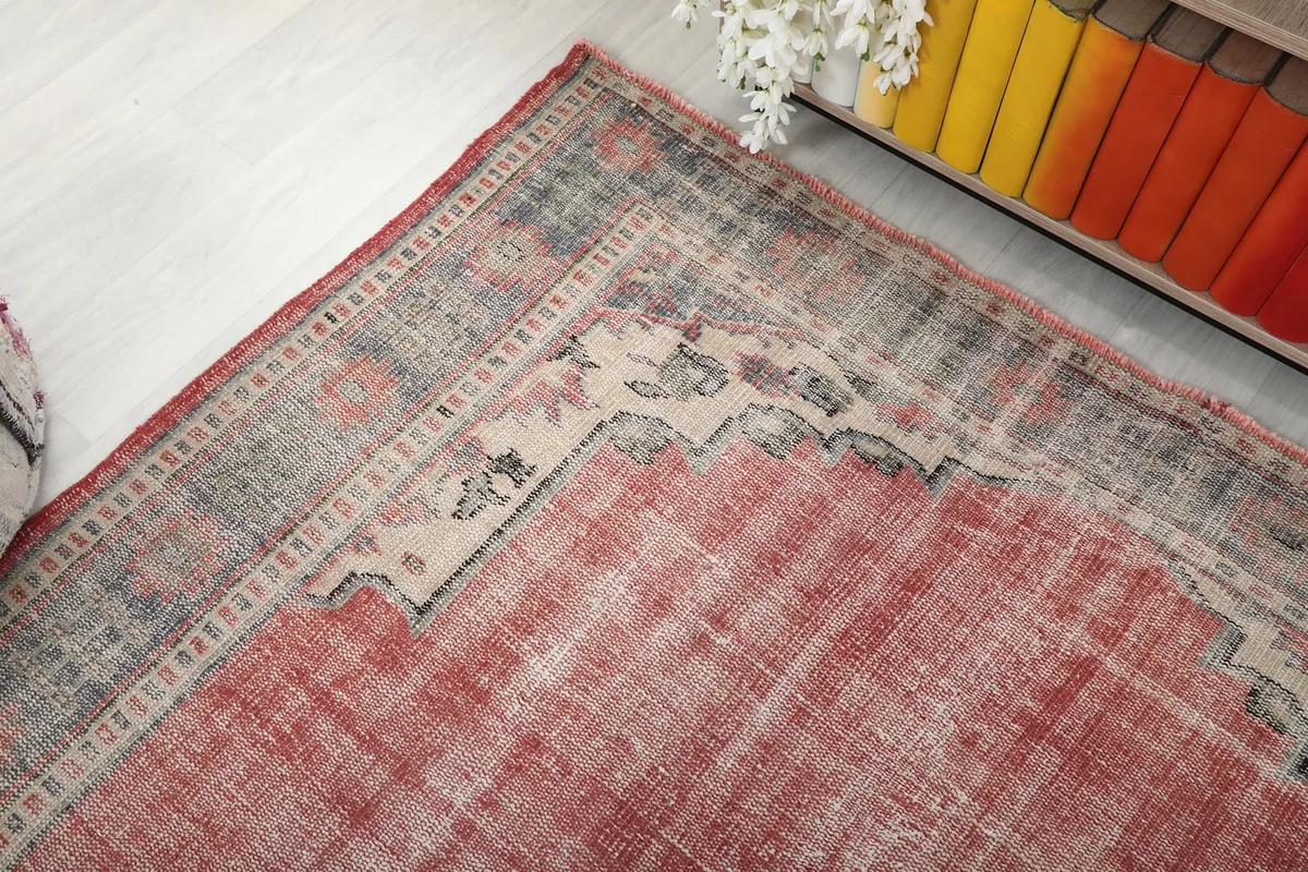 Corner view of the vintage rug showing the geometric border and faded rose field