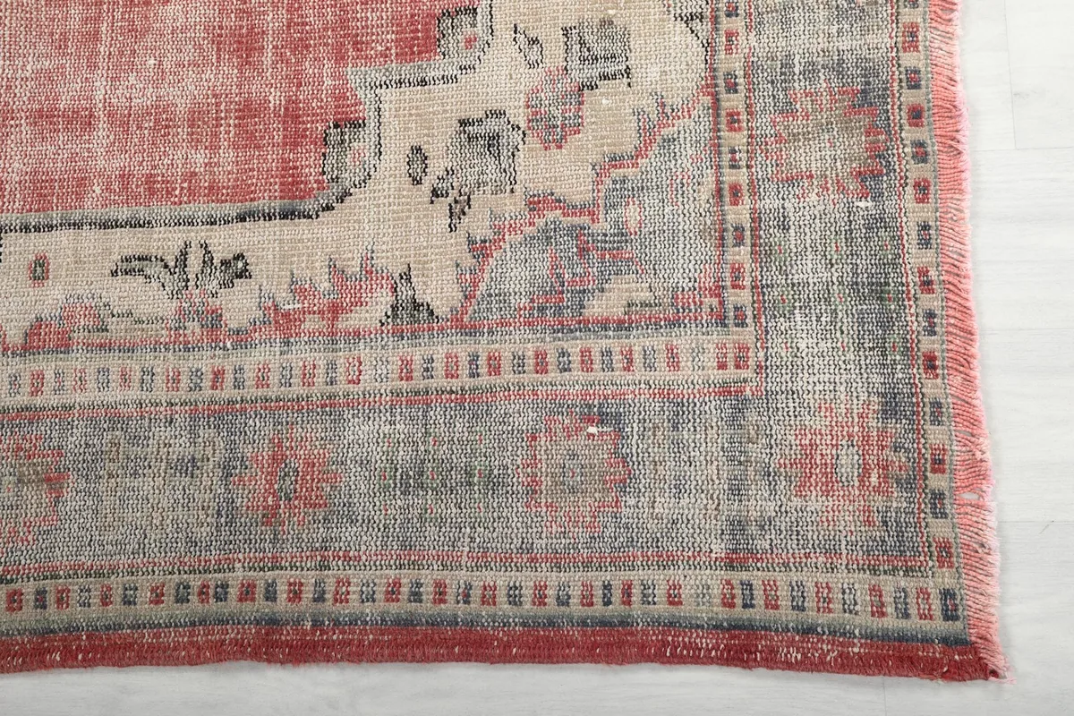 Detail of the gray and ivory border pattern and faded rose field of the vintage rug