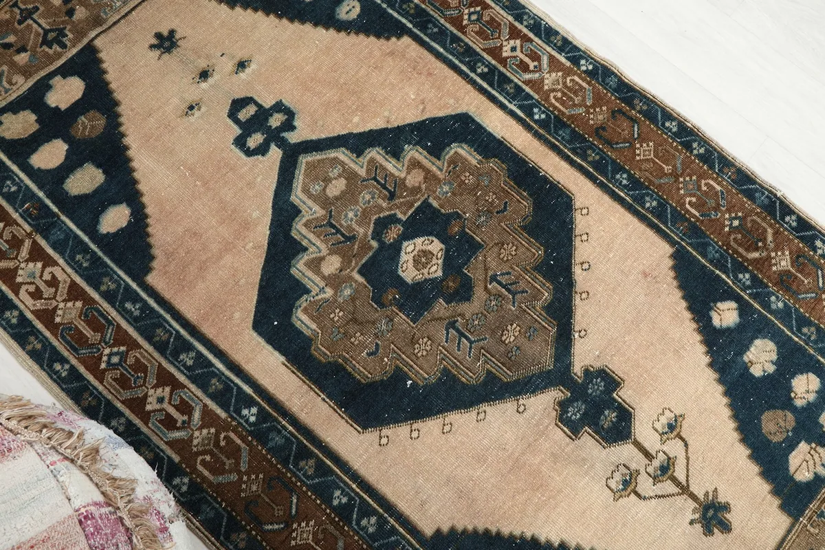 Diagonal view of the rug's beige field and navy geometric medallion