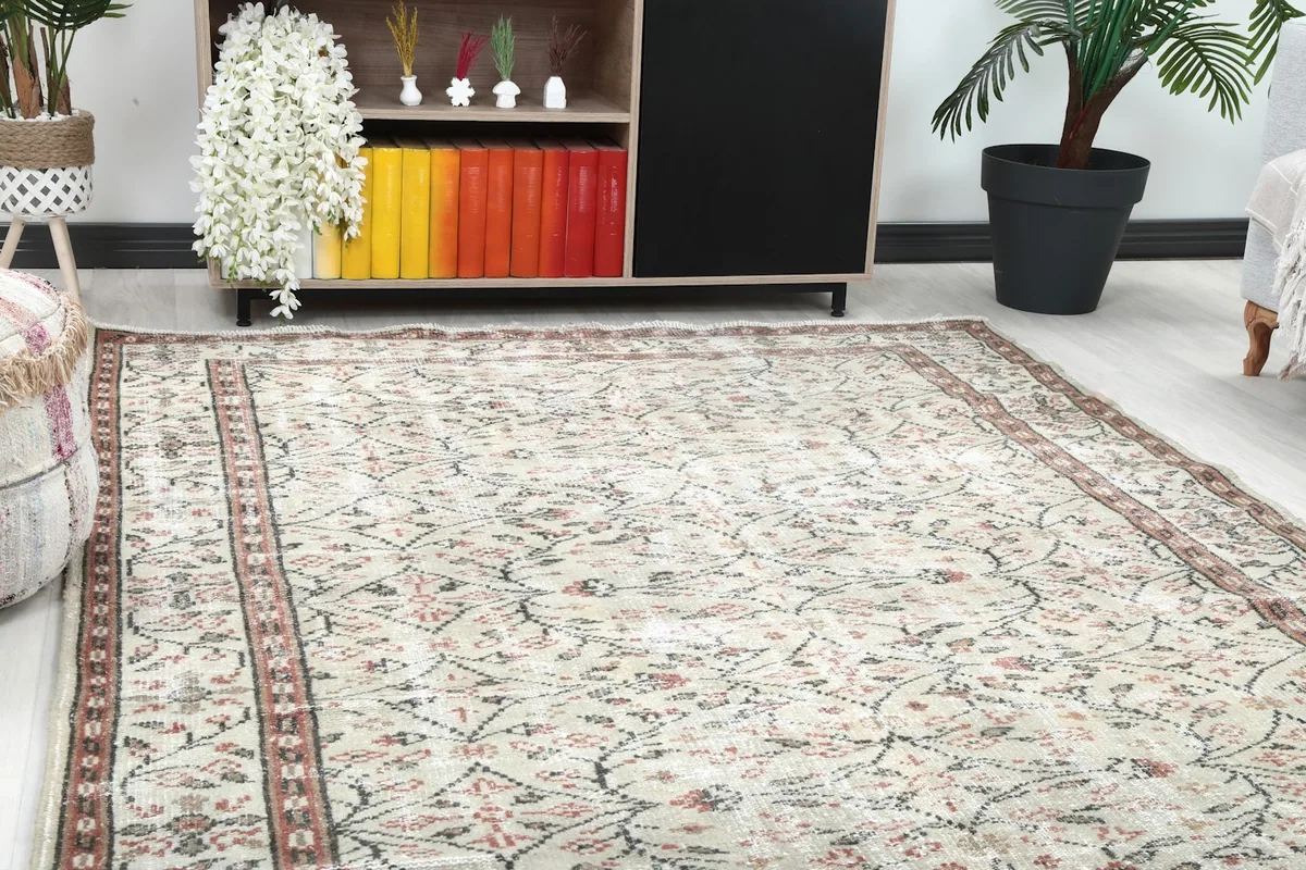 Close-up of the cream rug's pattern and rust border within a living room environment