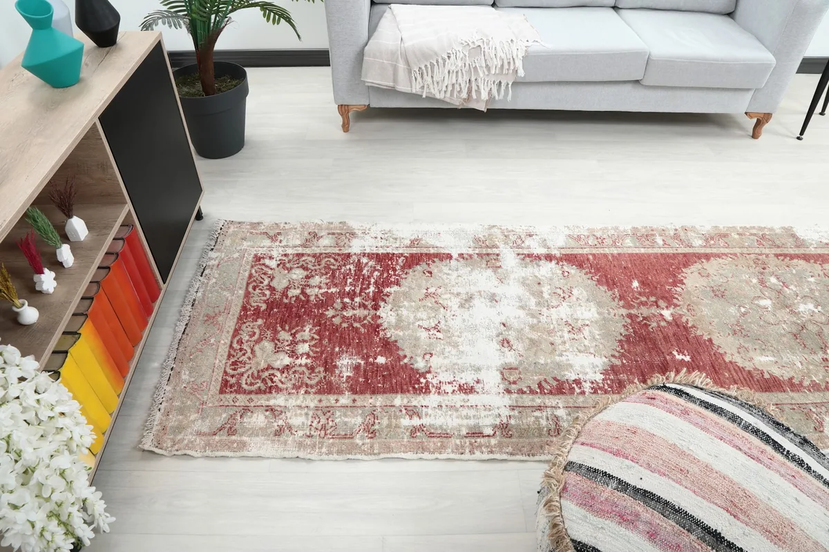 View of the runner rug stretching through a room, from a decorative ottoman towards a sofa