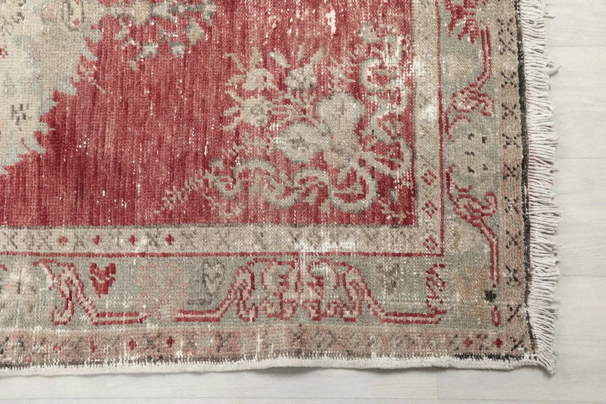 Close-up detail of the rug's border and corner, showing the distressed texture and fringe