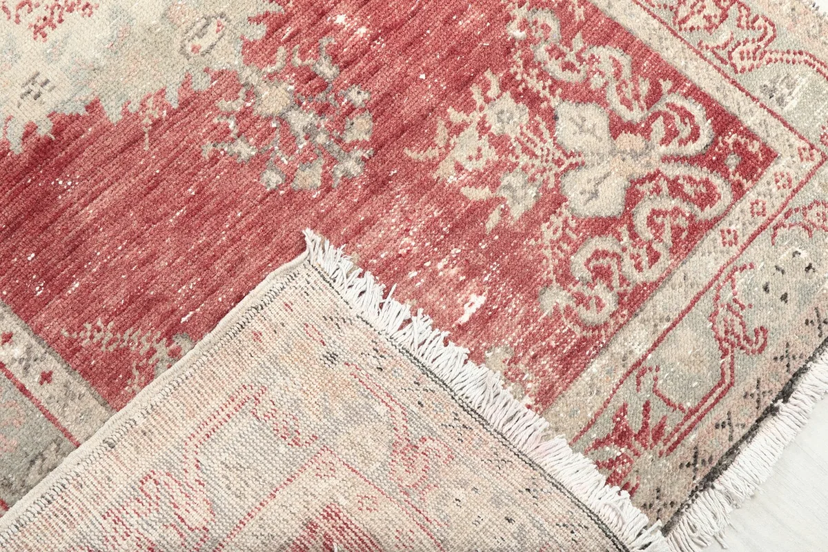Corner of the rug folded back to show the hand-knotted cotton foundation and wool pile