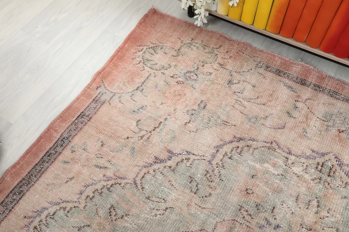 Angled view of one end of the rug, showing the faded colors and intricate patterns
