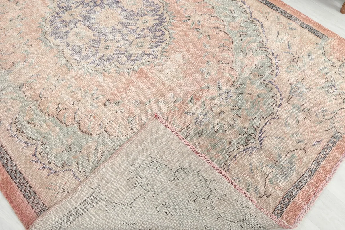 Folded corner of the rug, showing the wool pile on cotton foundation and a glimpse of the back