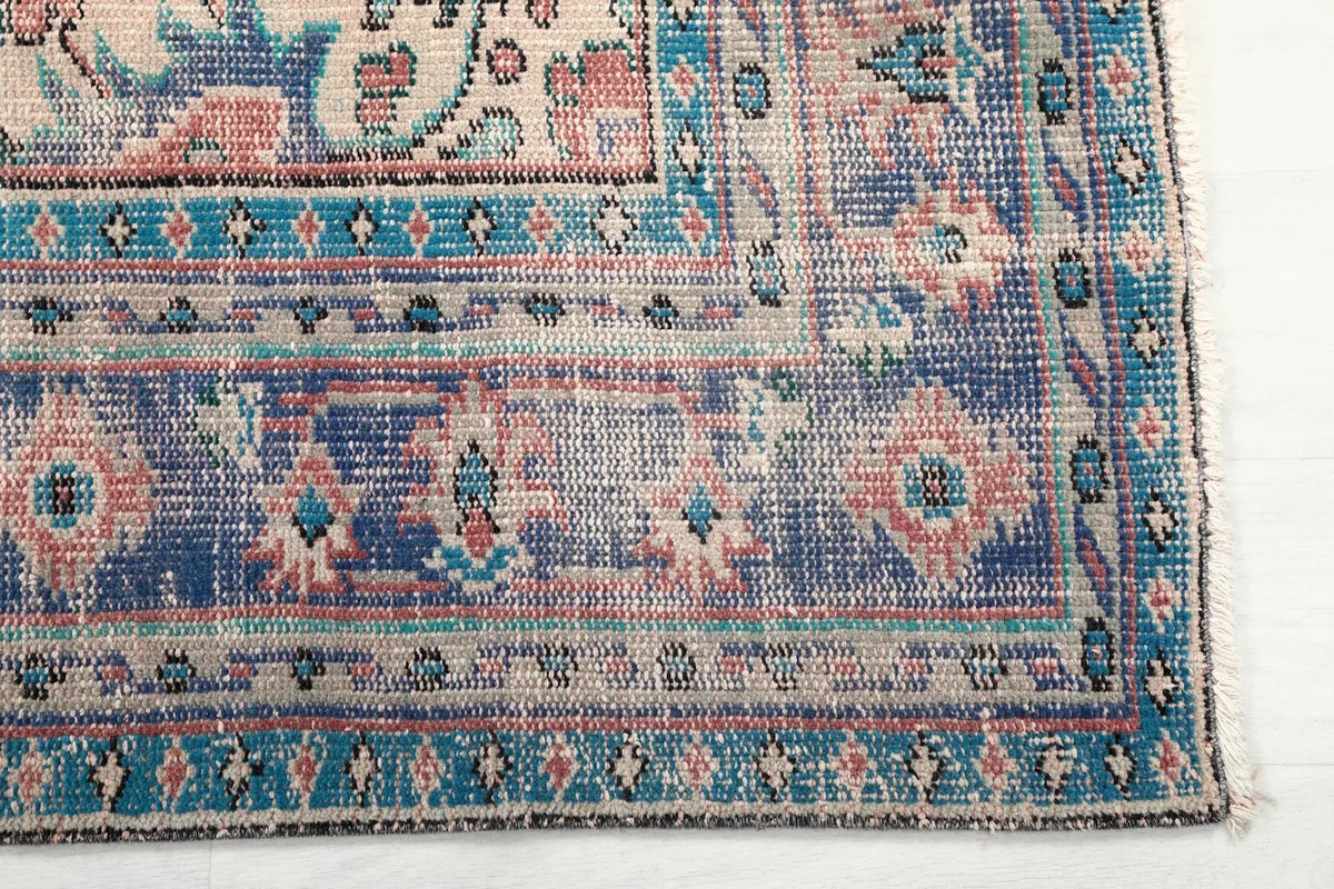 Detail of the blue border pattern and corner of the vintage hand-knotted rug