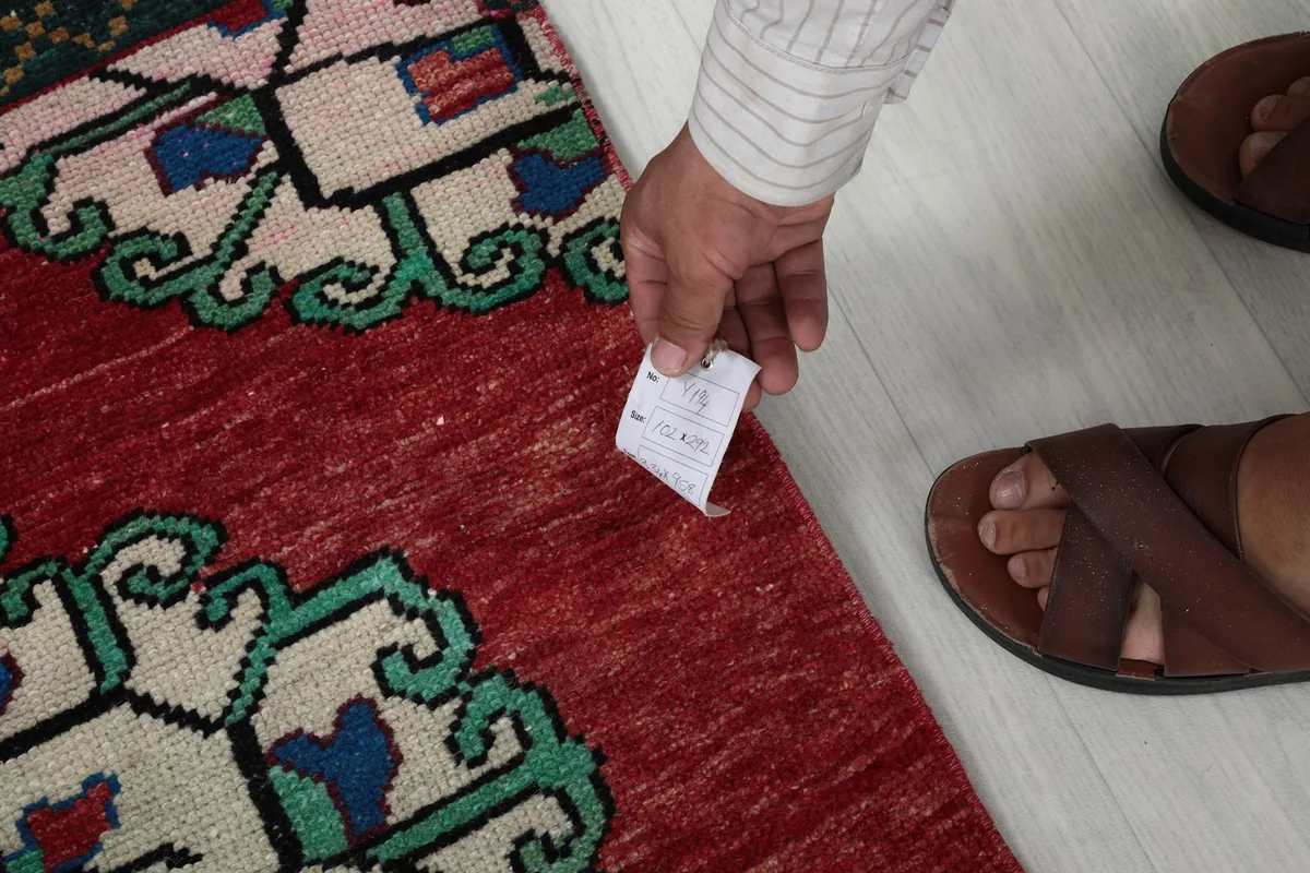 Hand touching the rug's low wool pile, demonstrating its texture and thickness.