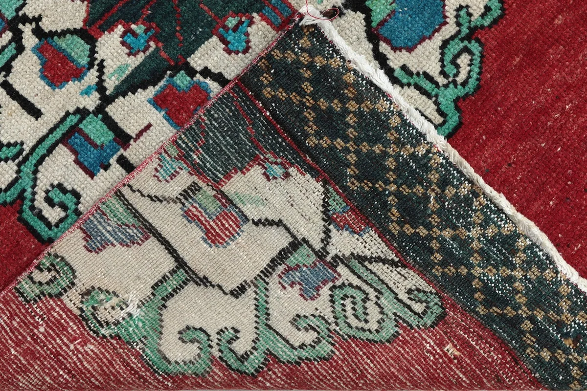 View of the rug's reverse side, showing the hand-knotted cotton foundation and wool pile.