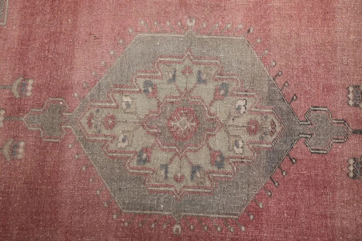 Close-up of the central gray medallion with subtle rose and blue accents in the rug's design.