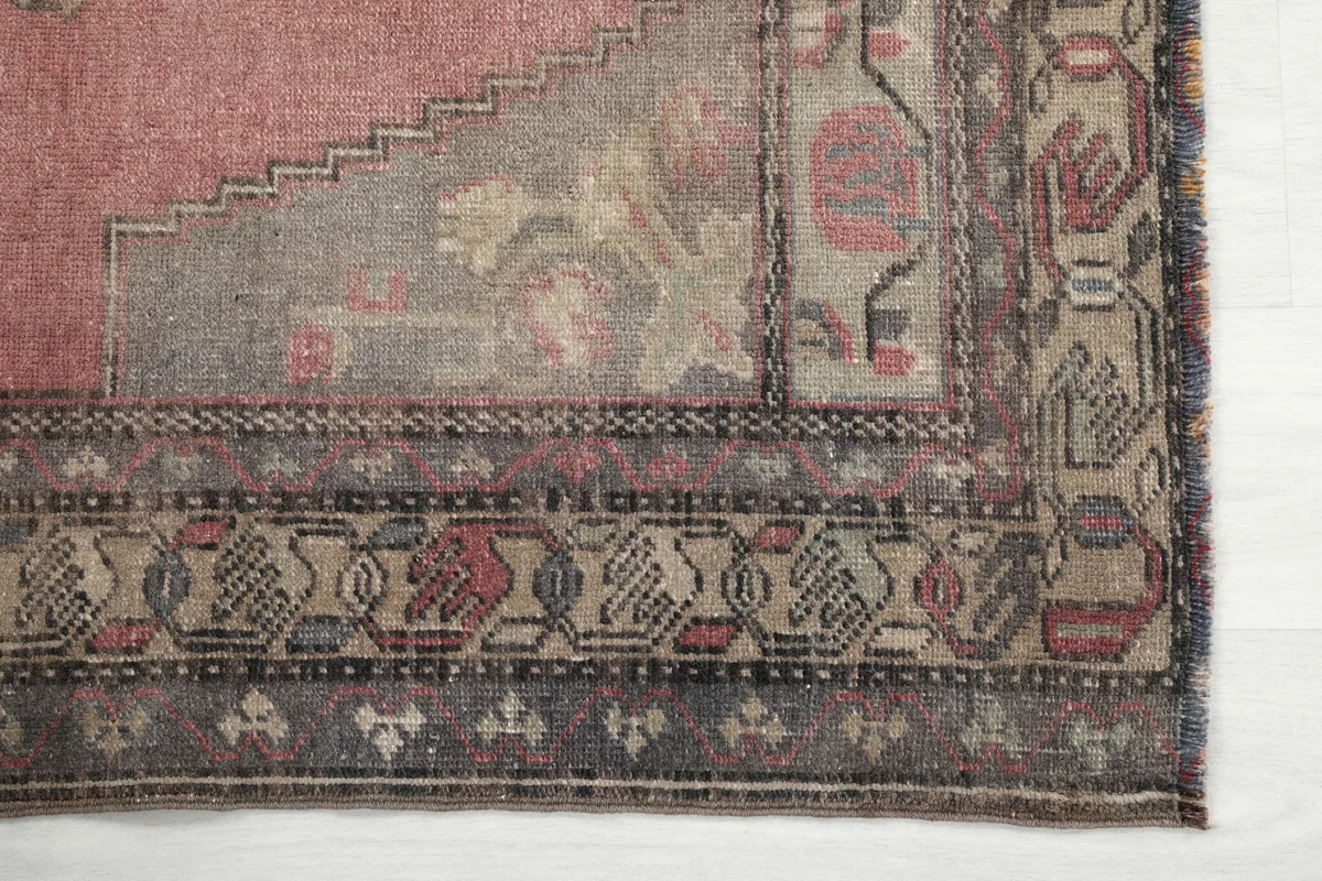 Detailed view of the intricate gray and rose border patterns of the vintage Anatolian rug.