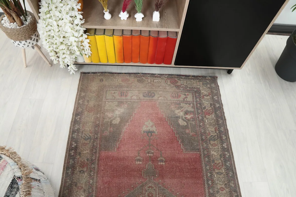 Overhead view of the vintage rose and gray rug in a room, showing its full length.